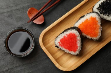 Lezzetli tobiko onigiri (Japon pirinç topları) siyah masada servis edilir.