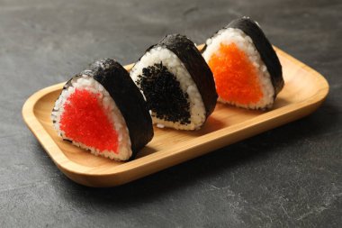 Lezzetli tobiko onigiri (Japon pirinç topları) siyah masada, yakın plan