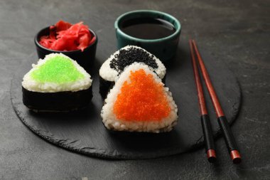 Lezzetli tobiko onigiri (Japon pirinç topları) siyah masada servis edilir.