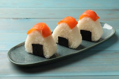 Lezzetli onigiri (Japon pirinç topları) mavi ahşap masada servis edilir, yakın plan.