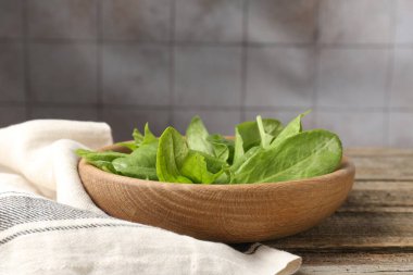 Taze yeşil kuş yaprakları kasede, ahşap masada, yakın plan.