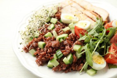 Beyaz ahşap masada kahverengi pirinçli leziz salata, yakın plan.