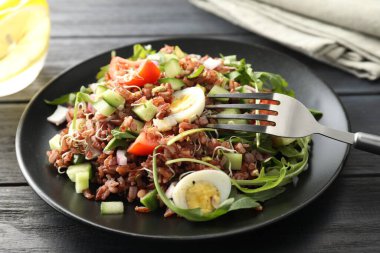 Siyah ahşap masada kahverengi pirinçli leziz salata, yakın plan.