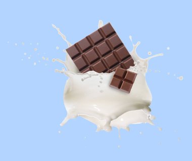 Nefis çikolata parçaları ve açık mavi arka planda havada sütün damlaları.