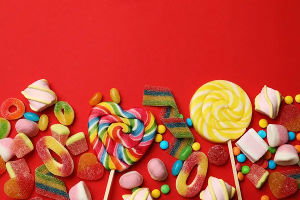 Farklı lezzetli şekerler ve kırmızı arka planda şekerlemeler. Metin için boşluk