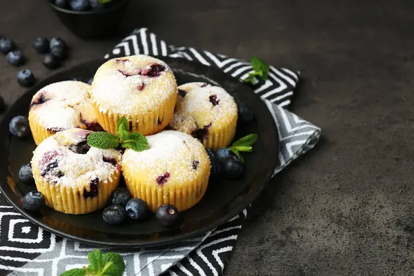 Yaban mersinli lezzetli çörekler, pudra şekeri ve siyah desenli masada nane şekeri, yakın plan. Metin için boşluk