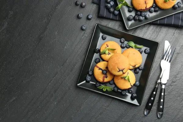 Yaban mersinli lezzetli kekler, nane ve çatal bıçak seti koyu dokulu masa, düz yatak. Metin için boşluk