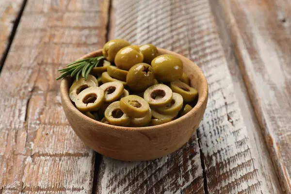 Lezzetli marine edilmiş zeytin halkaları, biberiye ve ahşap masadaki kasenin içindeki bütün halkalar, yakın plan.