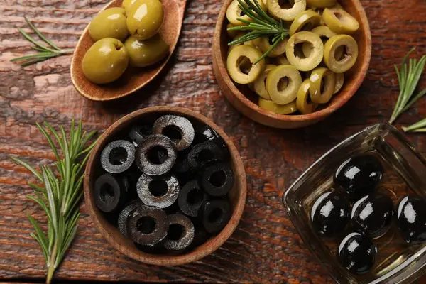 Farklı lezzetlerde marine edilmiş zeytin halkaları, bütün halkalar ve ahşap masa üzerinde biberiye, düz uzanış