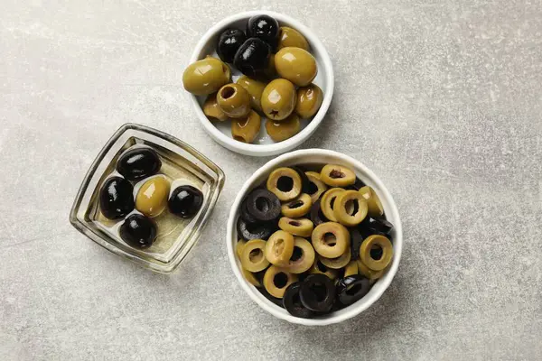 Farklı lezzetlerde marine edilmiş zeytin halkaları, gri desenli masadaki bütün halkalar, düz uzanmış.
