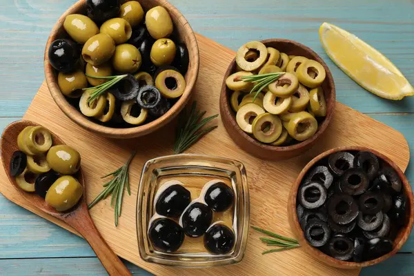 Farklı lezzetlerde marine edilmiş zeytin halkaları, tüm olanlar ve biberiye açık mavi ahşap masa, düz yatıyordu.