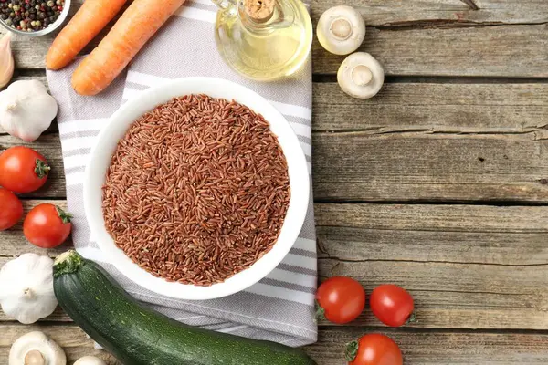 Tabaktaki çiğ kahverengi pirinç ahşap masadaki taze ürünlerin arasında, düz yerde. Metin için boşluk