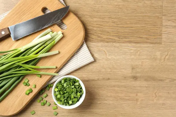 Tahta masada taze yeşil soğan ve bıçak, düz. Metin için boşluk