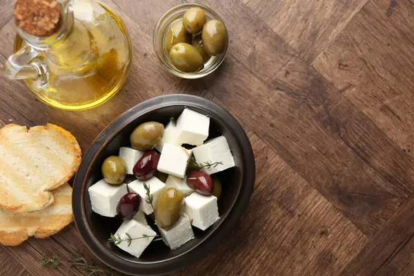 Salamura edilmiş zeytin, beyaz peynir, ekmek parçaları, ahşap masada yağ ve biberiye, düz yatak. Metin için boşluk