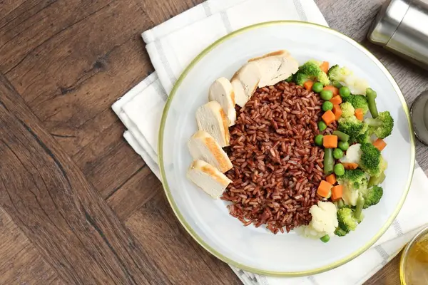 Tahta masada servis edilen tavuk ve sebzeli leziz kahverengi pirinç. Metin için boşluk