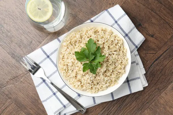Ahşap masada servis edilen maydanozlu lezzetli kahverengi pirinç.