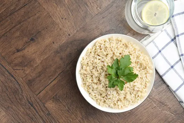 Ahşap masada servis edilen maydanozlu lezzetli kahverengi pirinç, üst manzara. Metin için boşluk