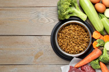 Beslenme kabında kurutulmuş hayvan maması ve ahşap masada doğal ürünler, düz yatak. Metin için boşluk