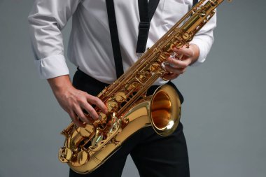 Gri arka planda saksafon çalan profesyonel müzisyen, yakın plan
