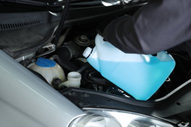 Plastik kutudan araba deposuna cam temizleyici döken adam, yakın plan.