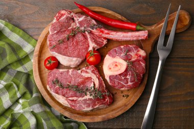 Çiğ et parçaları, baharatlar ve ürünler ahşap masa üzerinde, düz yatıyordu.