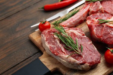 Çiğ sığır eti, biberiye ve domatesler ahşap masada, yakın plan. Metin için boşluk