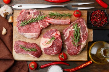 Çiğ et parçaları, baharatlar ve ürünler ahşap masa üzerinde, düz yatıyordu.