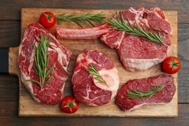 Tahta masada çiğ et, biberiye ve domates parçaları.