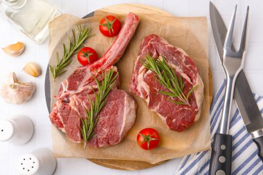 Çiğ et parçaları, ürünler ve baharatlar beyaz döşeme üzerinde, düz yatıyordu.