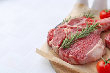 Bir parça çiğ et, biberiye ve domatesler beyaz fayanslı masada, yakın plan. Metin için boşluk