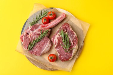 Çiğ et parçaları, biberiye ve domatesler sarı masada, üst tarafta.