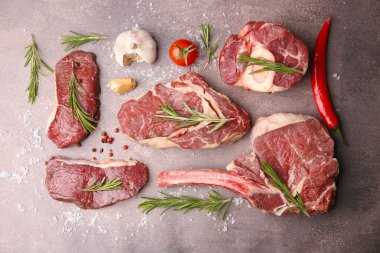 Flat lay composition with pieces of raw beef, salt, rosemary and products on brown textured table