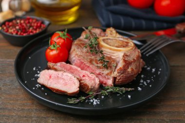 Lezzetli et parçaları, ahşap masada baharatlar ve domatesler, yakın plan.