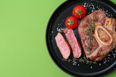 Lezzetli et parçaları, yeşil arka planda baharatlar ve domatesler, üst manzara. Metin için boşluk