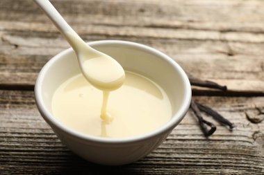 Lezzetli vanilyalı yoğurtlu sütü ahşap masadaki kaşıkla yakın plan çekiyoruz.