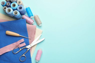 Açık mavi arka planda farklı dikiş malzemeleri, düz bir zemin. Metin için boşluk