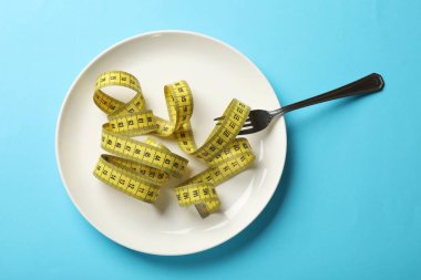 Bulimia. Açık mavi zemin üzerinde çatal ve mezura ile plaka, üst görünüm