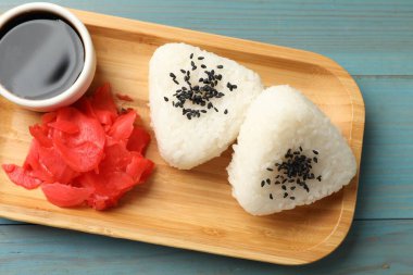 Pirinç topları (onigiri), soya sosu ve açık mavi ahşap masa üzerinde turşulu zencefil, üst manzara. Geleneksel Japon yemeği