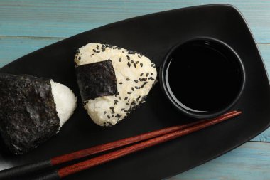 Pirinç topları (onigiri) açık mavi ahşap masa üzerinde servis edilir. Geleneksel Japon yemeği
