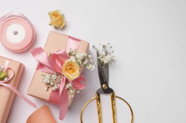 Çiçekçi. Beyaz arka planda kutular, çiçekler, makas ve kurdele düz. Metin için boşluk