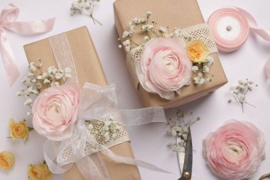 Çiçekçi. Beyaz arka planda kutular, çiçekler, kurdele ve makas düz konum