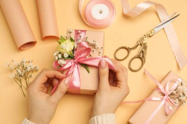 Çiçek kutuları, çiçekler, makas ve bej arka planda kurdele olan çiçekçi.