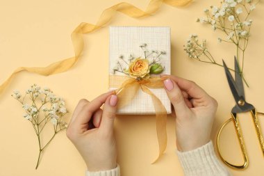 Çiçek kutusu, çiçek, makas ve bej arka planda kurdele olan bir çiçekçi.