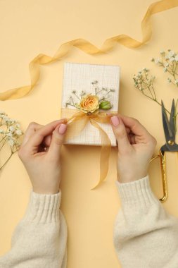 Çiçek kutusu, çiçek, makas ve bej arka planda kurdele olan bir çiçekçi.