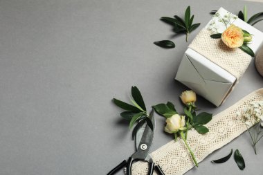 Çiçekçi. Kutu, çiçekler, yapraklar ve makas gri arka planda, yukarıda. Metin için boşluk