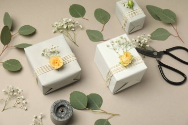 Çiçekçi. Kutular, çiçekler, makas ve yanan mum açık gri arkaplanda