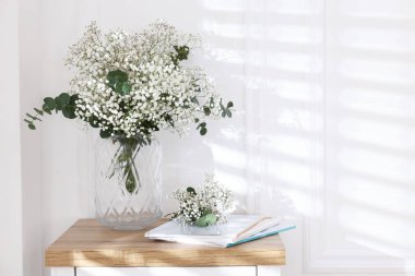 Evdeki masasında okaliptüs dalları vazoda ve dergiler olan güzel gypila çiçekleri. Metin için boşluk