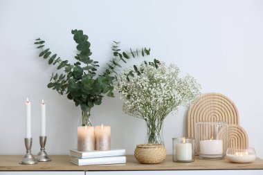 Güzel çikila çiçekleri, okaliptüs dalları, yanan mumlar ve evde klozet üzerine kitaplar.