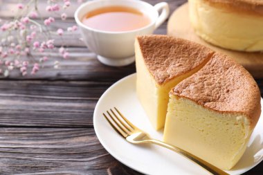 Lezzetli Japon Castella sünger keki, çay, çingene çiçekleri ve ahşap masa çatalı, yakın plan. Metin için boşluk