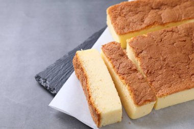 Tasty Japanese Castella sponge cake on grey table, closeup. Space for text